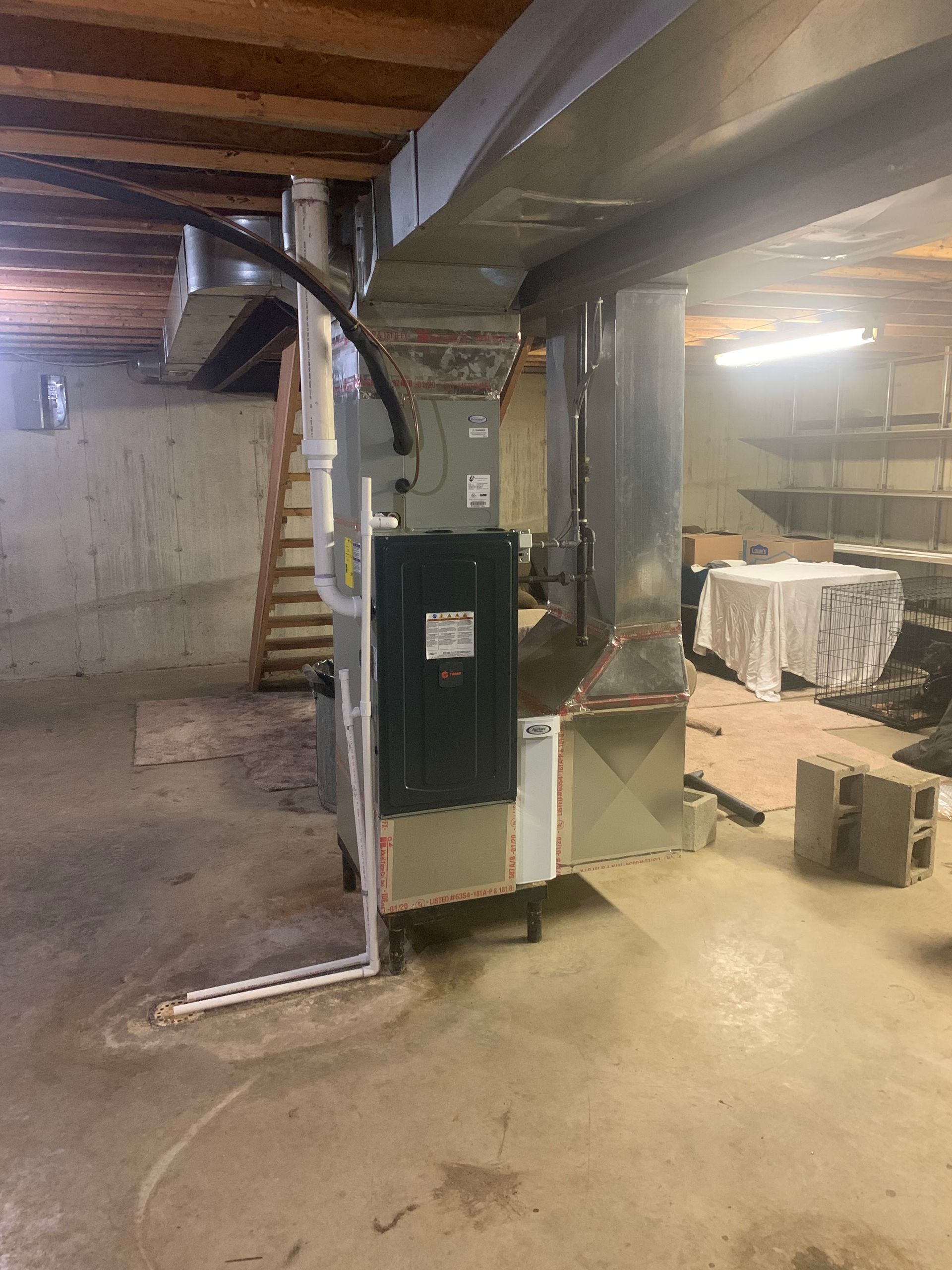 A basement with a furnace and stairs in it.