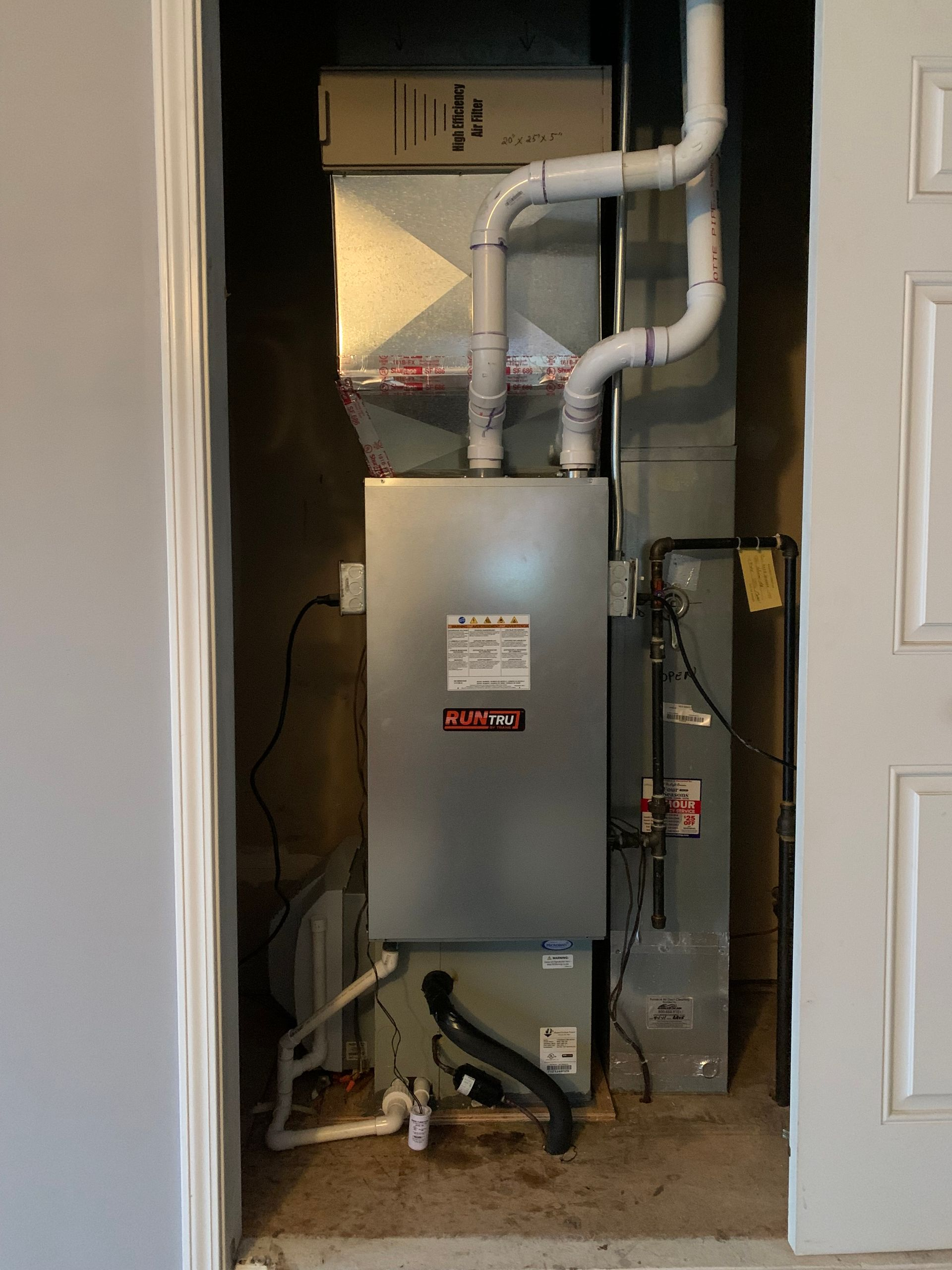 Furnace and air handler unit in a closet. Ductwork and PVC pipes visible.