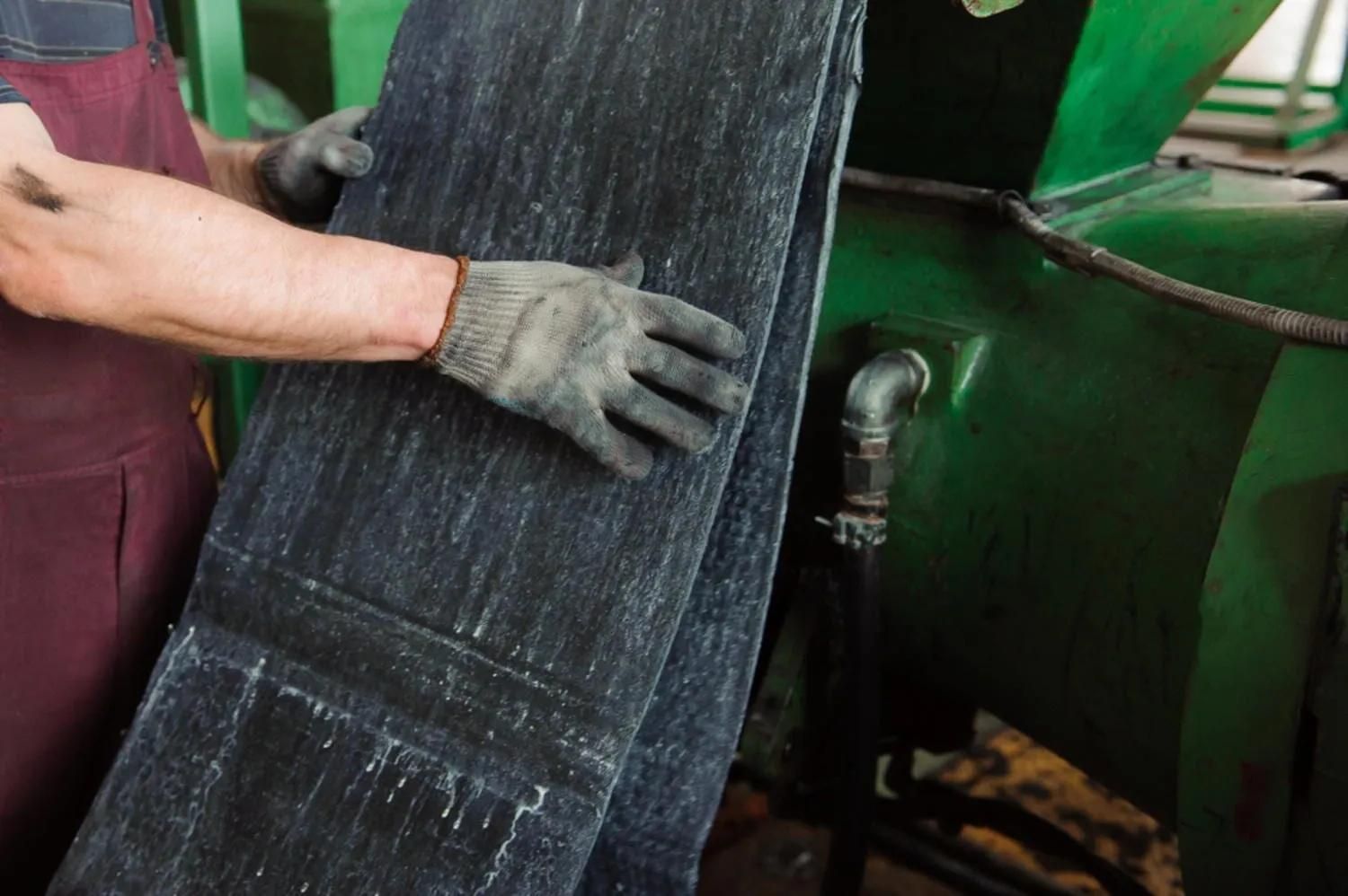 A Man Wearing Gloves Is Holding A Pair Of Jeans In A Factory — HardRok Engineering Pty Ltd In Mount Isa, QLD