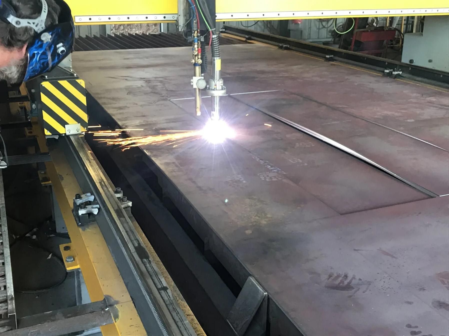 Industrial plasma cutter cutting a large steel plate, with bright sparks in a factory setting — HardRok Engineering Pty Ltd In Mount Isa, QLD