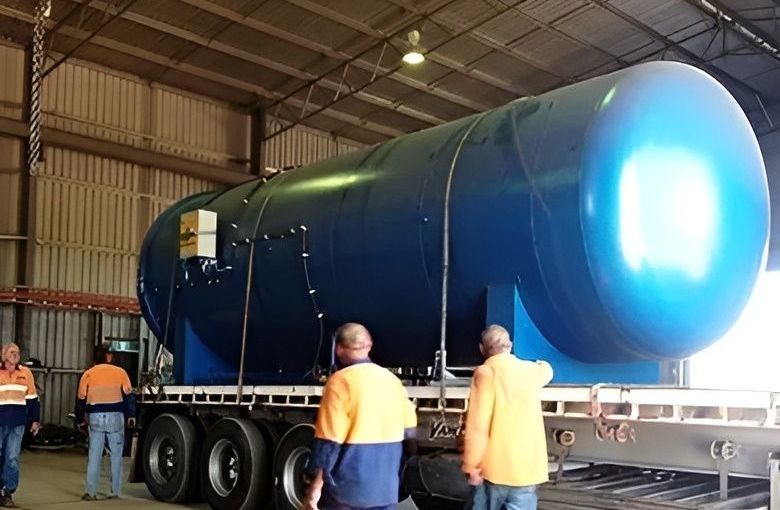 Two Men Are Walking In Front Of A Large Blue Tank — HardRok Engineering Pty Ltd In Mount Isa, QLD