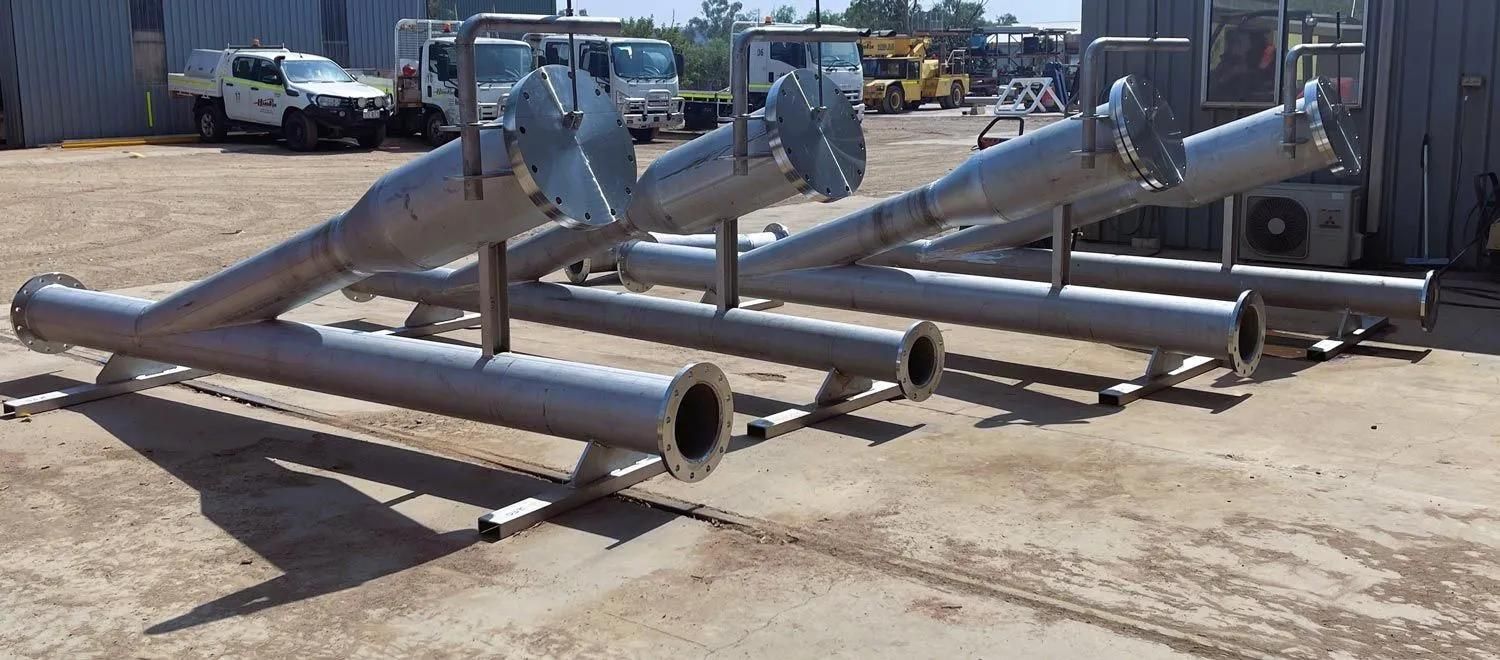 A Bunch Of Stainless Steel Pipes Are Sitting On The Ground In A Parking Lot — HardRok Engineering Pty Ltd In Mount Isa, QLD