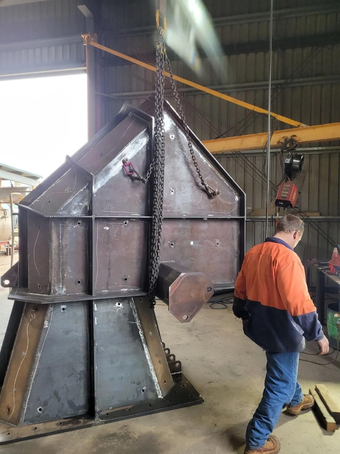 A Man Is Standing Next To A Large Metal Structure In A Factory — HardRok Engineering Pty Ltd In Tennant Creek, NT