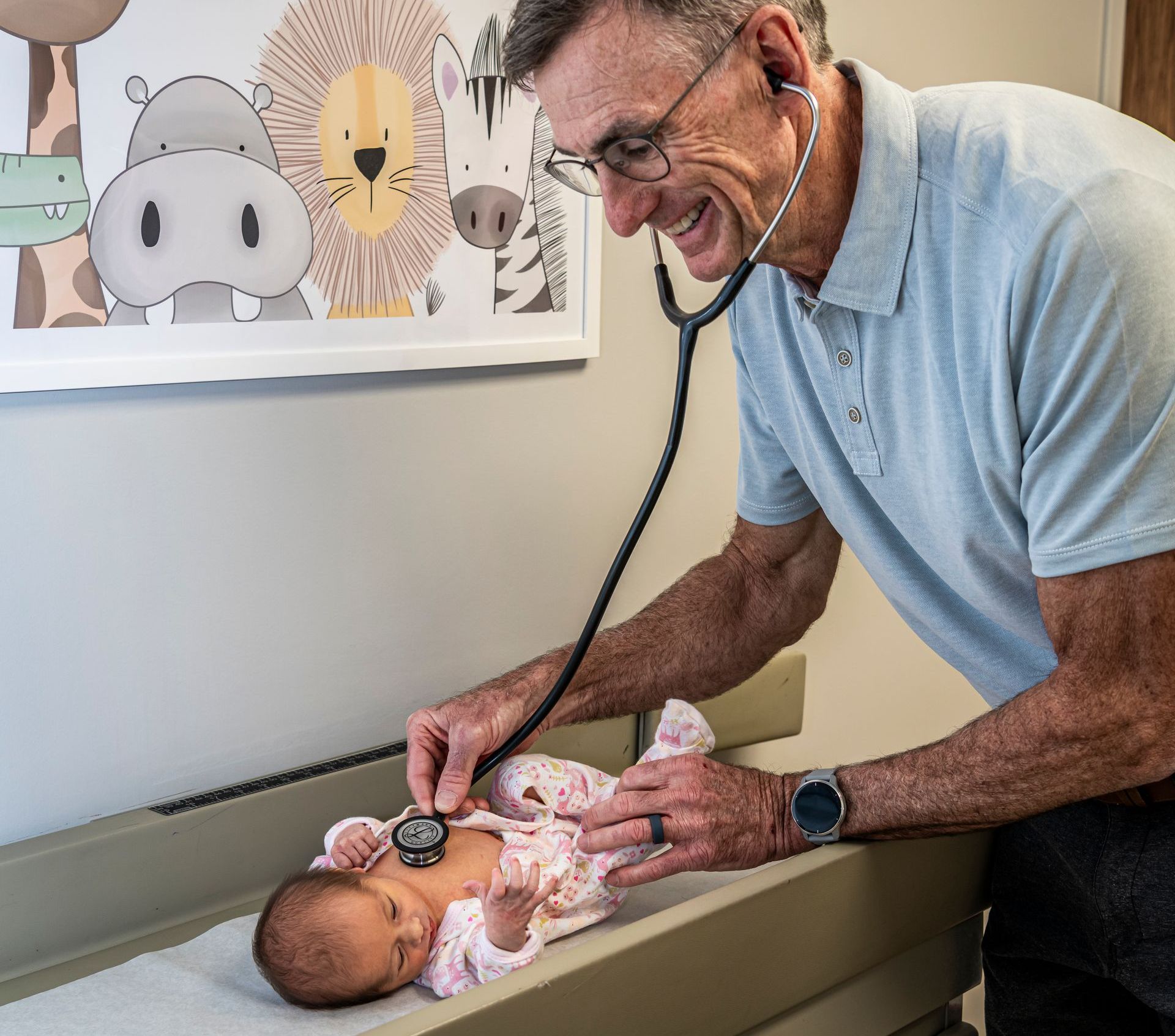 A pediatrician is listening to a baby 's heartbeat with a stethoscope