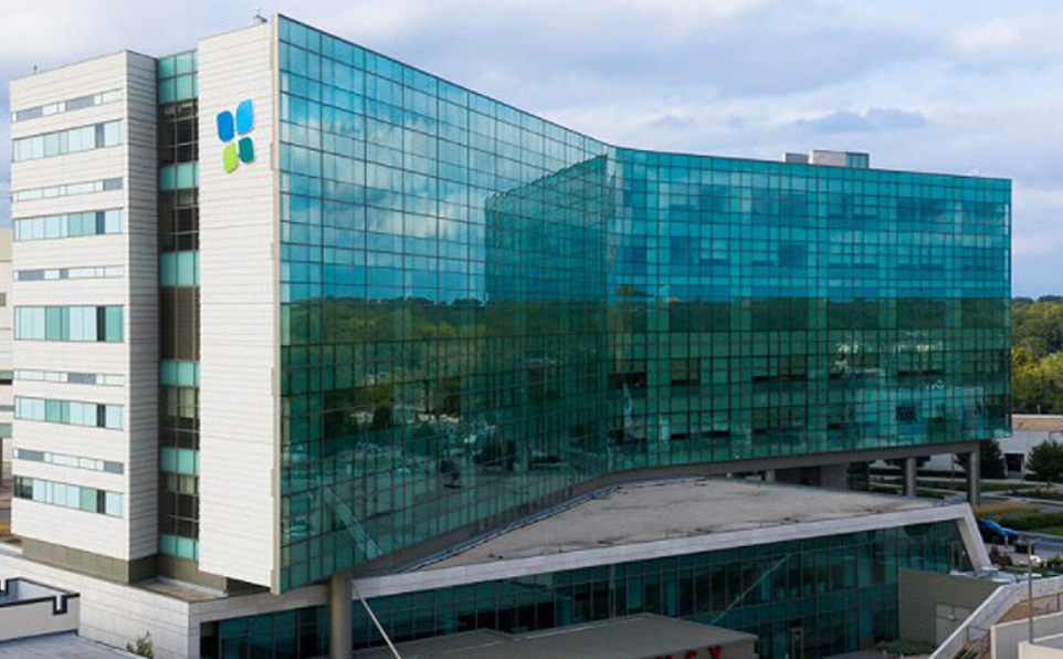 Modern glass office building with turquoise windows and a white exterior wall