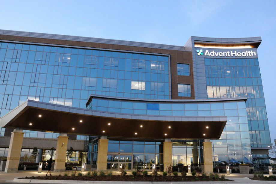 AdventHealth hospital exterior with glass facade and covered entrance at dusk