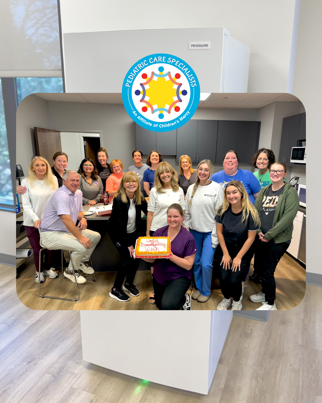 Group of people posing in a bright office, smiling around a large white cabinet with a colorful logo on top.