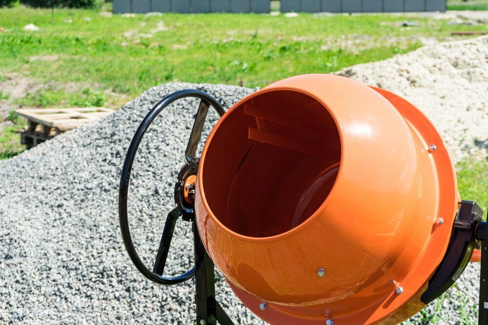 An Orange Concrete Mixer is Sitting on Top of a Pile of Gravel — Hamblin Hire in Albury, NSW