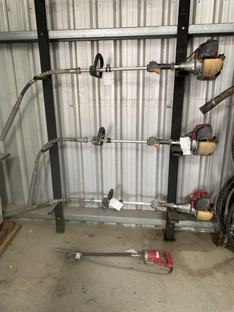 A Row of Lawn Mower Blades Hanging on a Rack in a Garage — Hamblin Hire in Albury, NSW