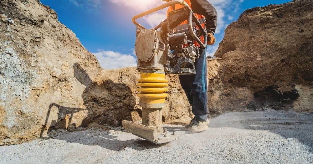 A Man is Using a Concrete Saw to Cut a Concrete Driveway — Hamblin Hire in Albury, NSW