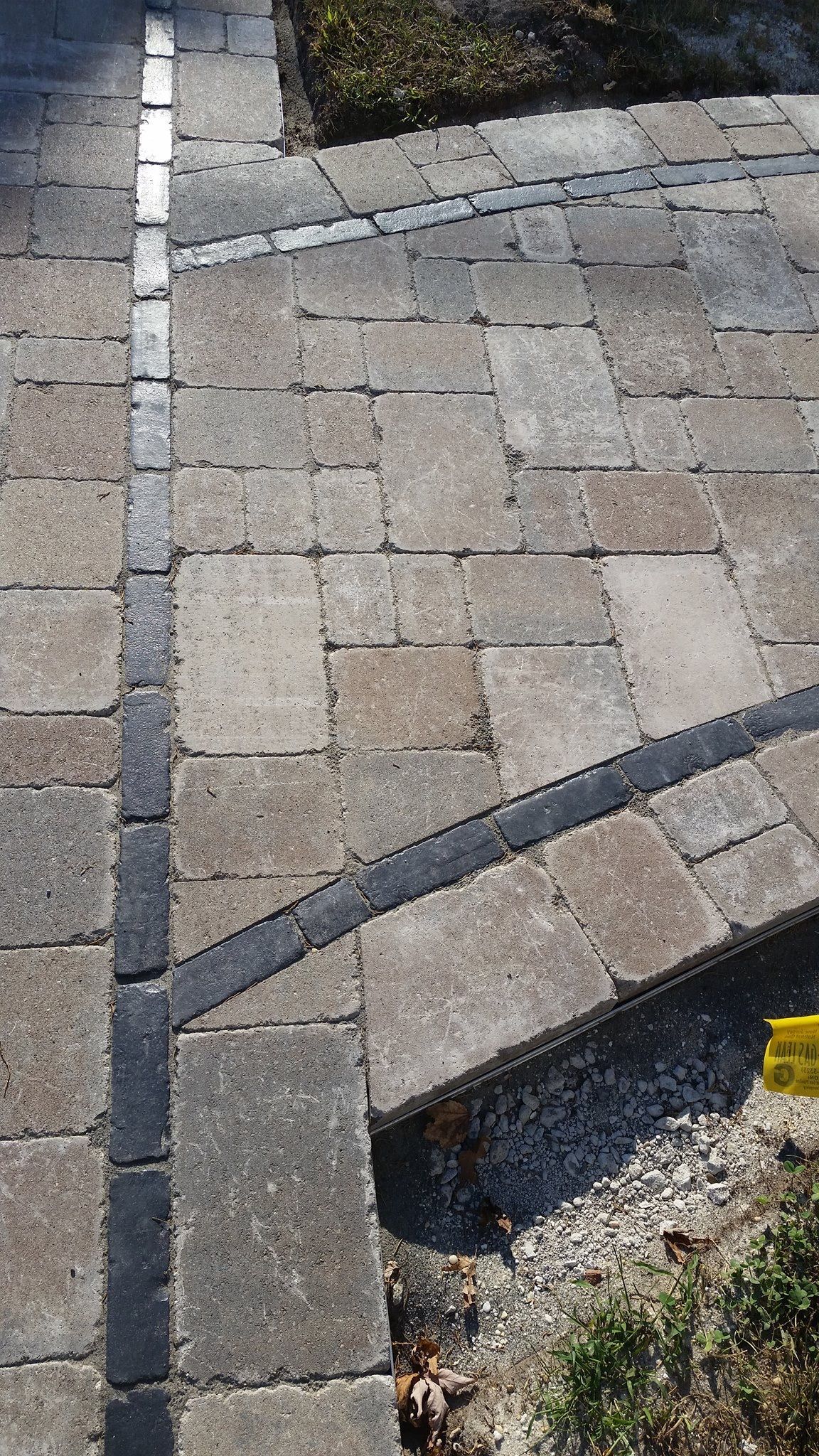 Brick walkway with dark linear drain and border.