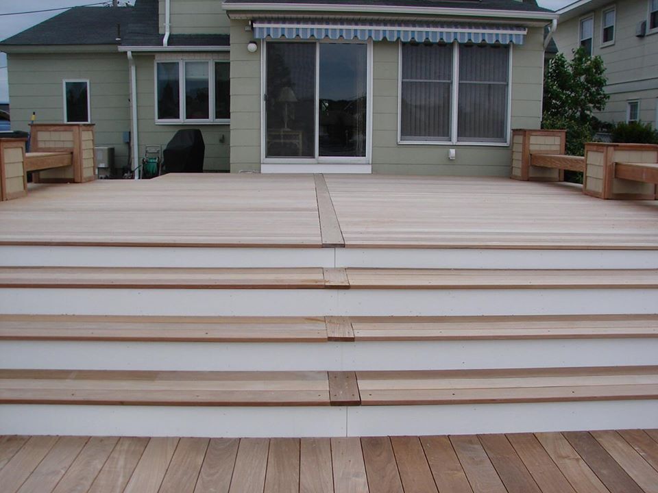 Wooden deck with steps leading up to a house with large sliding glass door.