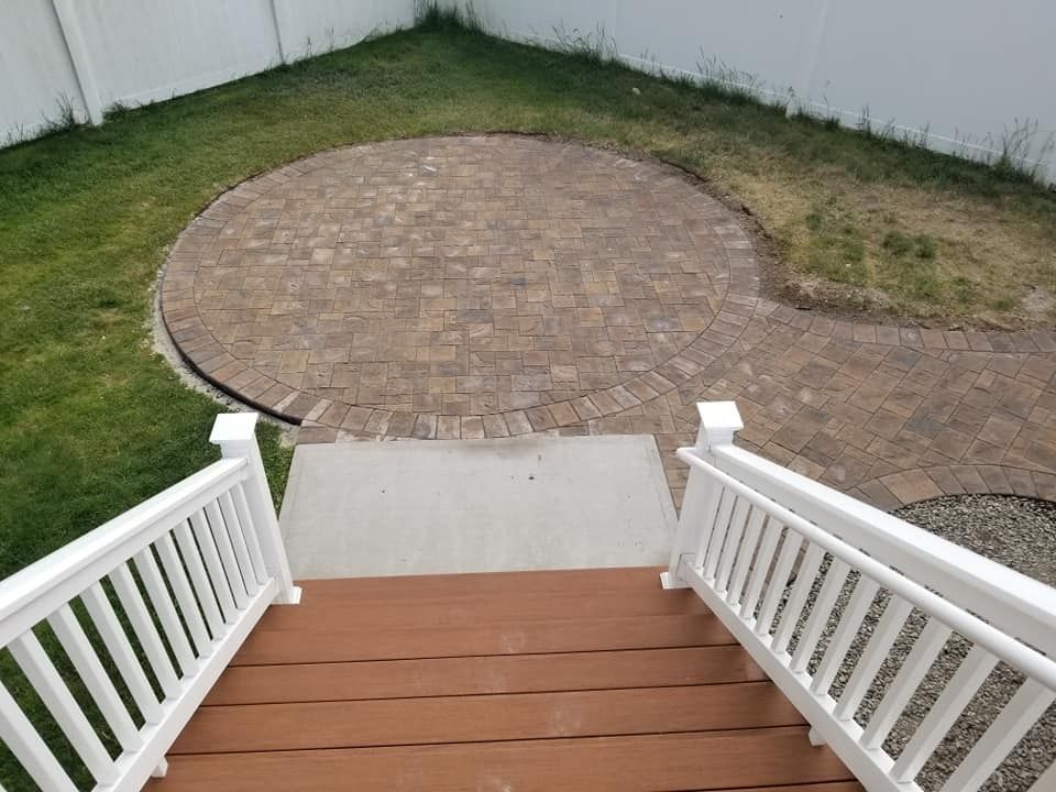Overhead view of a deck with brown steps and white railings leading to a brick patio.