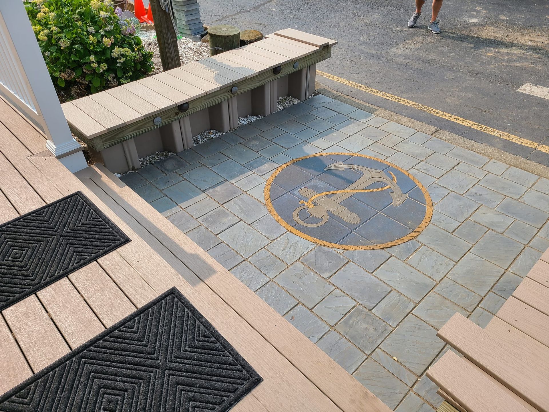 Stone patio with anchor emblem and wooden bench.