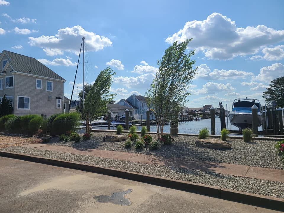 Coastal houses with docks and boats on a canal under a blue sky with fluffy clouds.