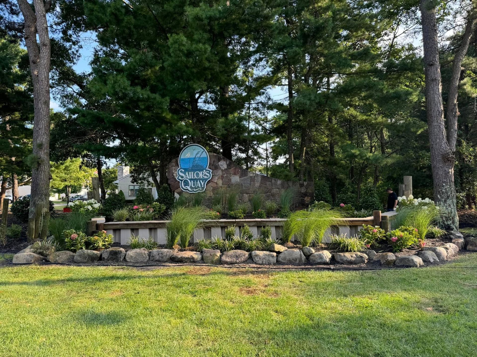 Sign for Sunrise Cove, set in a stone and flower bed surrounded by trees.