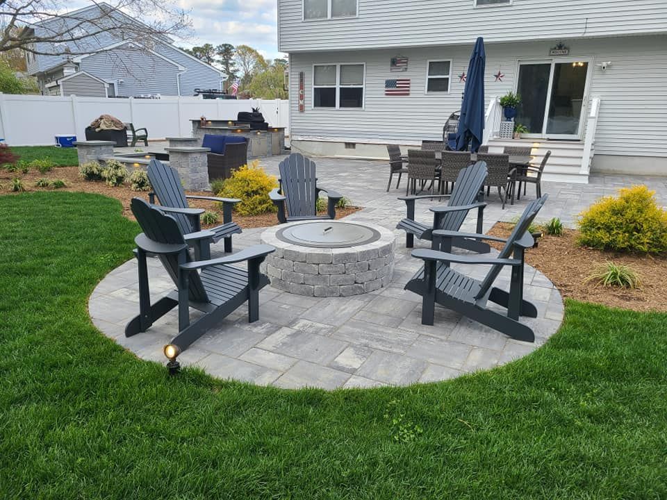 Outdoor patio with fire pit, Adirondack chairs, and dining area by a house.