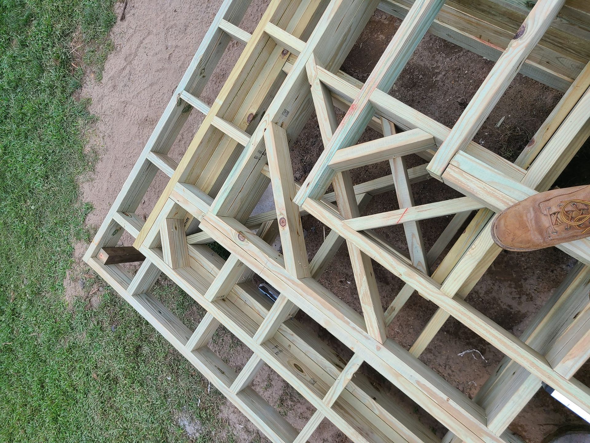 Wooden deck frame under construction outdoors on grass.