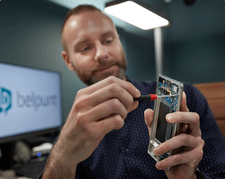 A man is fixing a cell phone with a screwdriver.