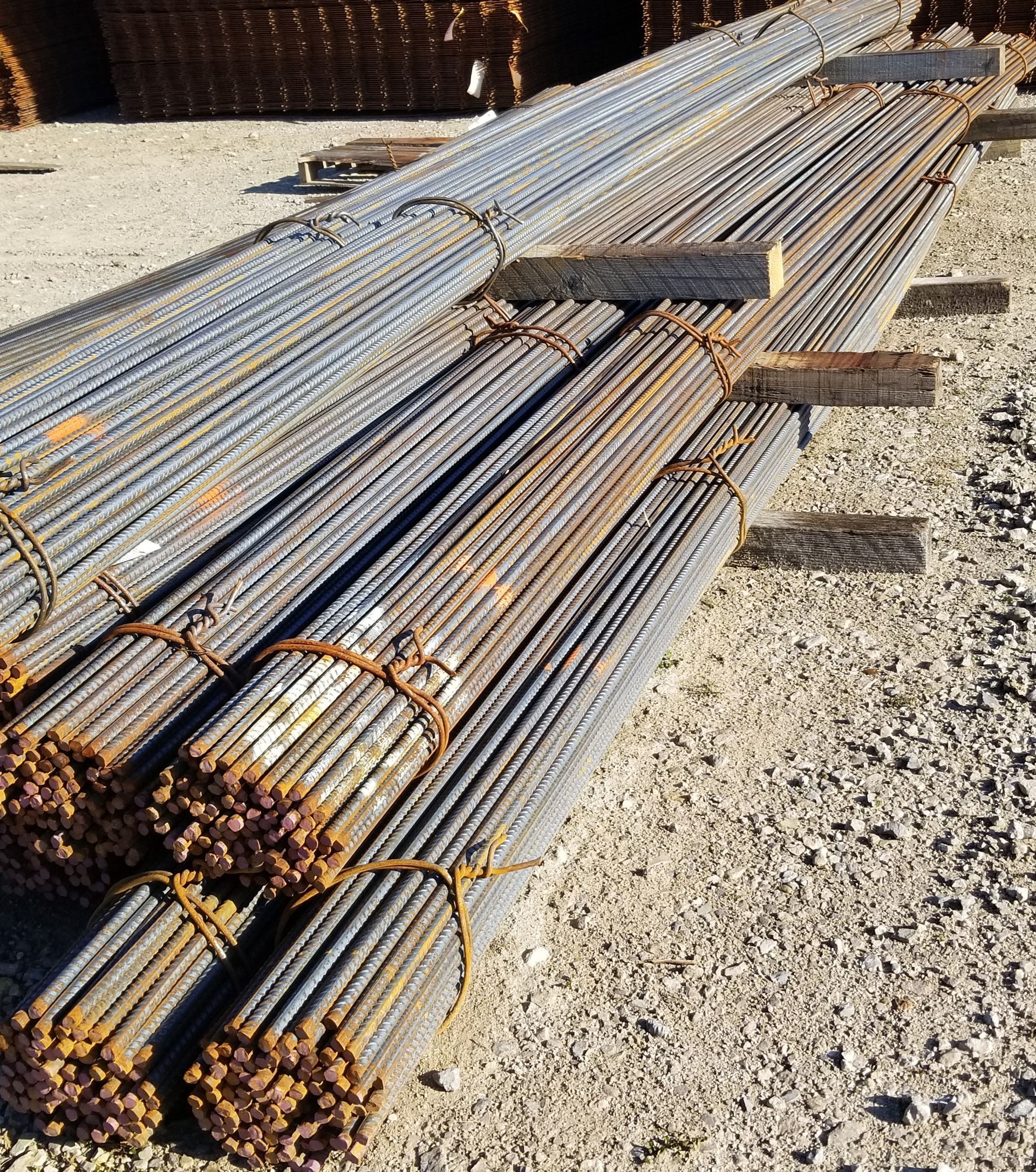 Bundles of steel rebar tied together, resting on wooden supports outdoors.