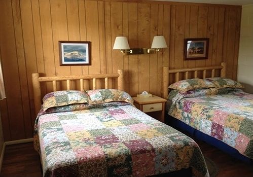 A bedroom with two beds and two lamps on the wall