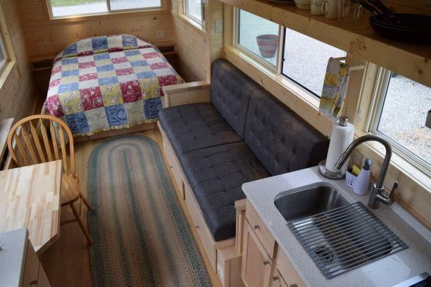 An aerial view of a small house with a bed , couch , table and sink.