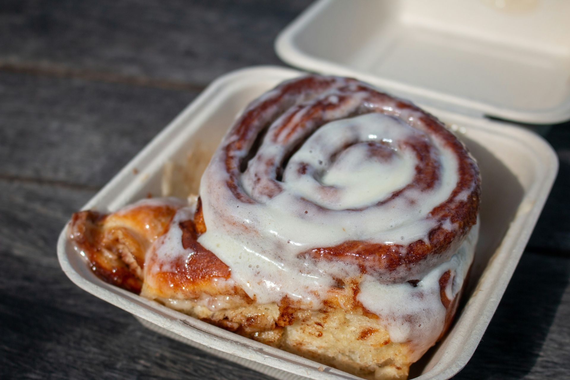 A close up of a cinnamon roll in a styrofoam container.