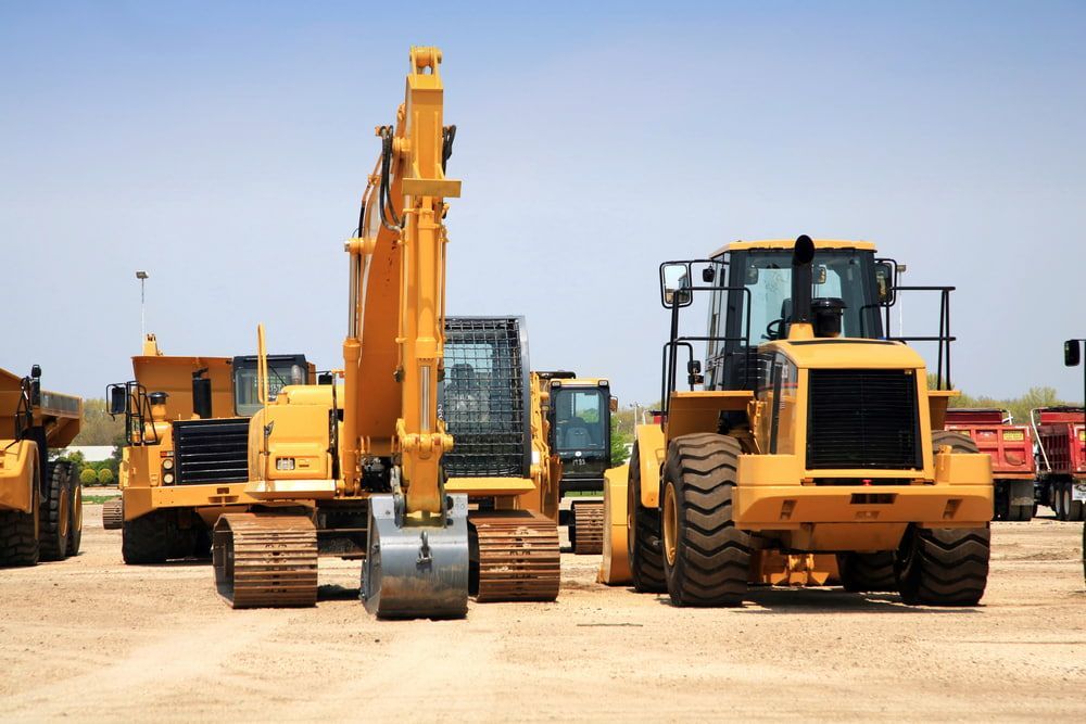Yellow Construction Vehicles Parked on a Dirt Lot Under a Clear Sky — Dirt Werx in Nowra, NSW