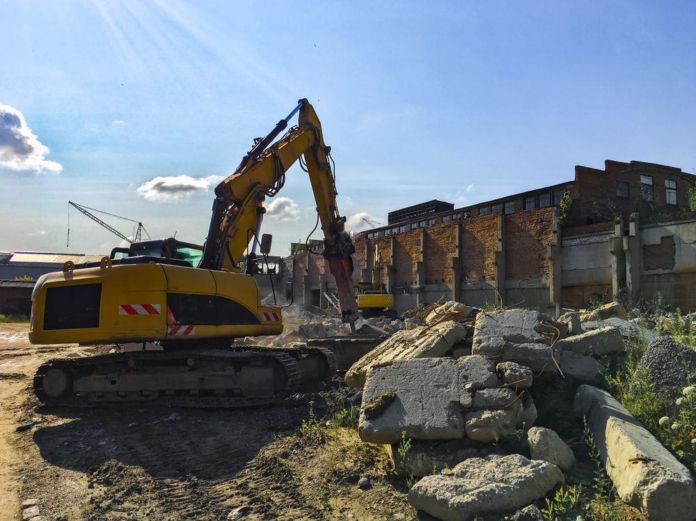 Yellow Excavator Demolishing A Brick Building — Dirt Werx in Nowra, NSW