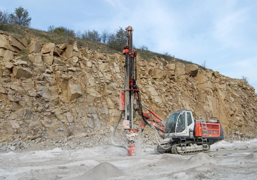 Excavator With Drill, Drilling Into a Rocky Hillside at a Quarry — Dirt Werx in Nowra, NSW