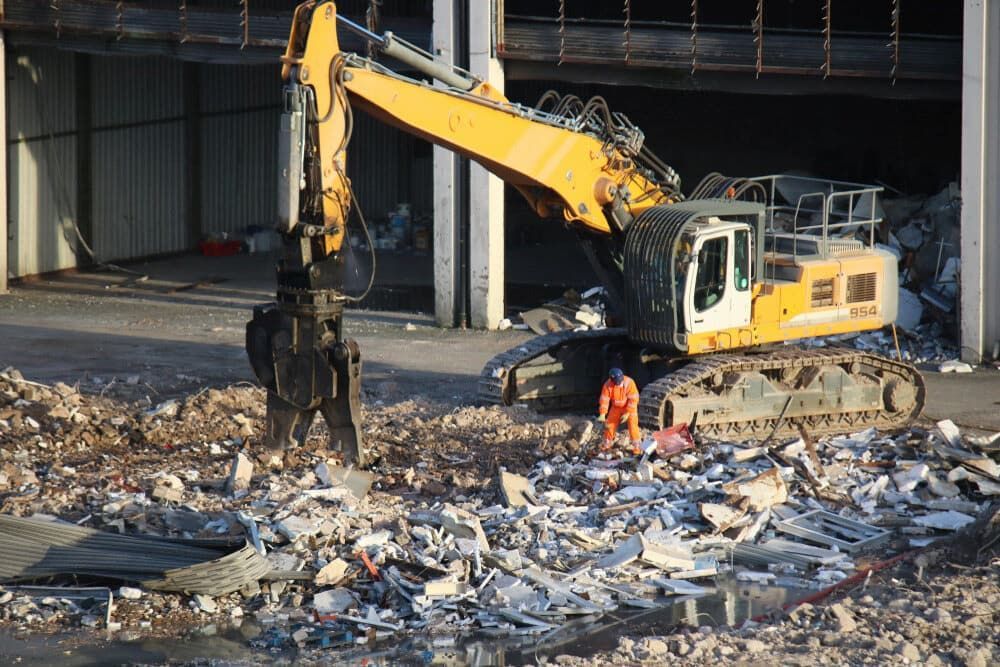 Yellow Excavator Demolishing a Building; Debris on the Ground — Dirt Werx in Ulladulla, NSW