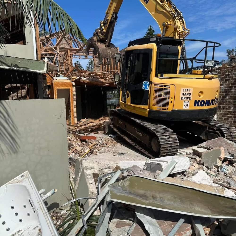 Yellow Excavator Demolishing a Building — Dirt Werx in Nowra, NSW