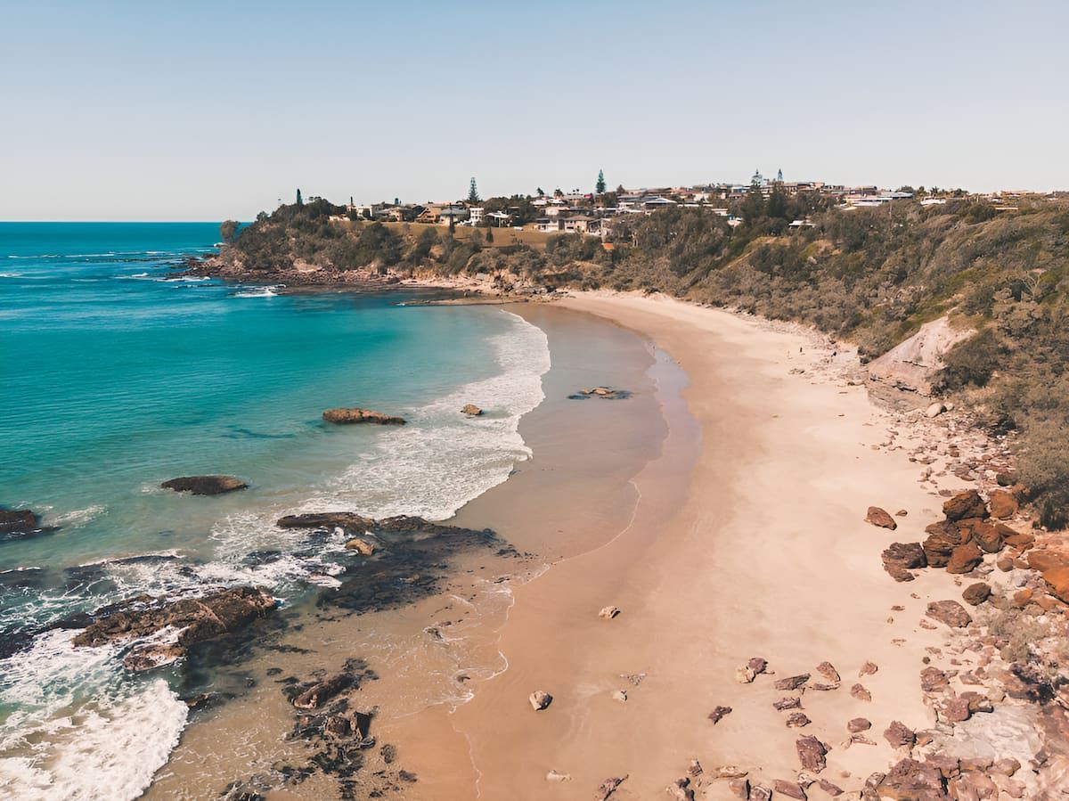 Beach With Turquoise Water, Golden Sand, Rocky Coast, and a Town — Dirt Werx in Batemans Bay, NSW