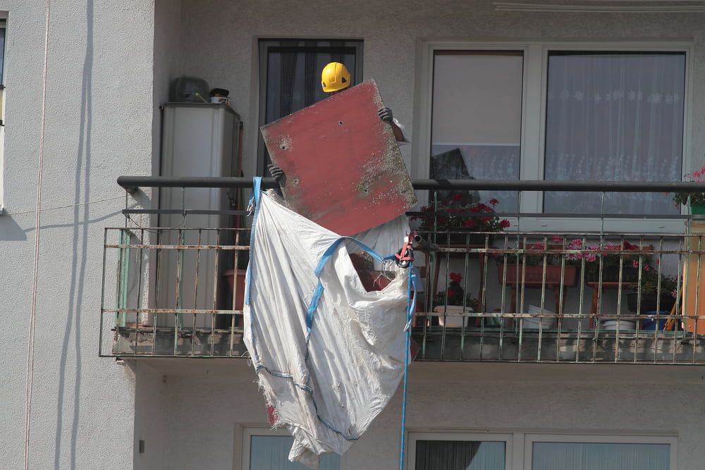 A White Tarp and Red Board Hanging From a Balcony Railing — Dirt Werx in Merimbula, NSW