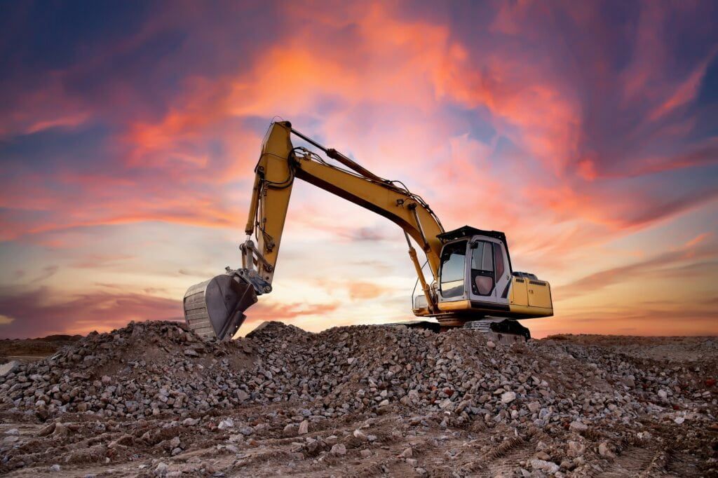 Yellow Excavator on a Pile of Dirt Against a Colorful Sunset Sky — Dirt Werx in Southern Highlands, NSW