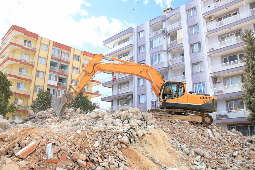 Yellow Excavator Demolishing a Building and Rubble Pile — Dirt Werx in Nowra, NSW