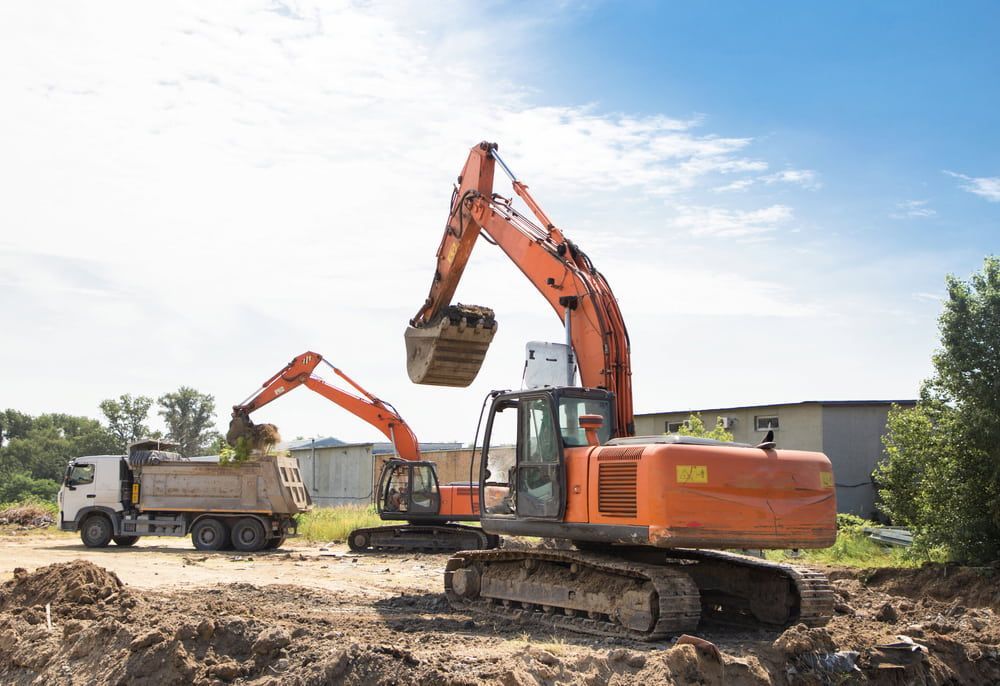 Two Orange Excavators Loading a Dump Truck on a Construction Site — Dirt Werx in Shellharbour, NSW