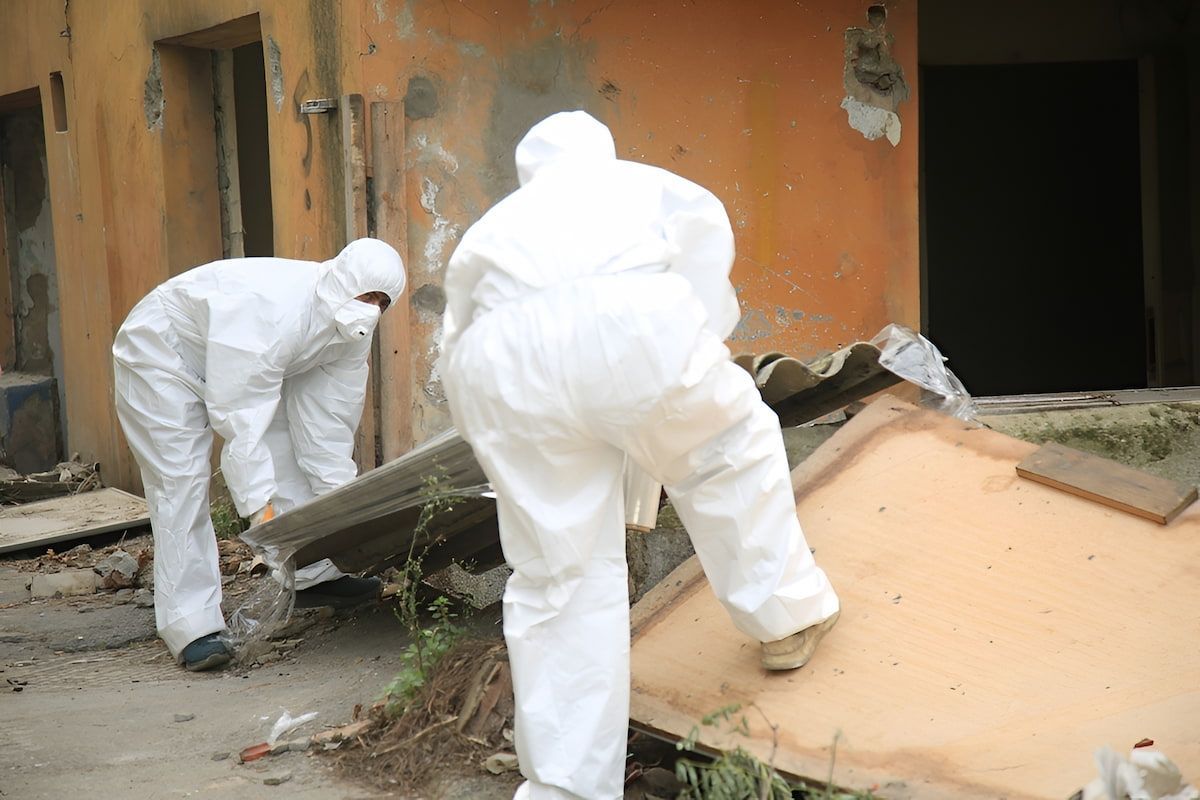 Two People in White Protective Suits Removing Debris From a Damaged Building — Dirt Werx in Nowra, NSW
