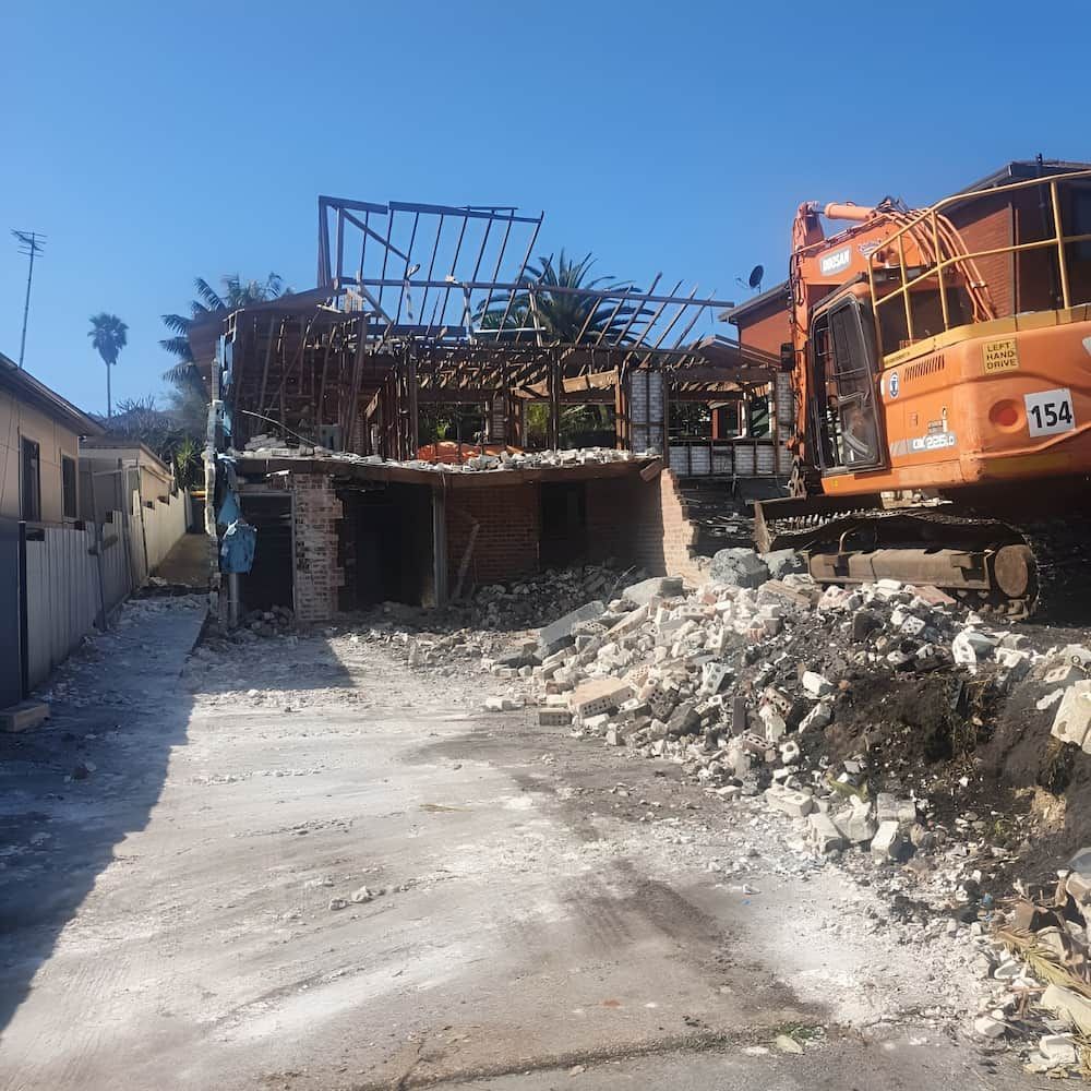 Demolished Building With Exposed Frame, Rubble Pile, and an Excavator — Dirt Werx in Nowra, NSW