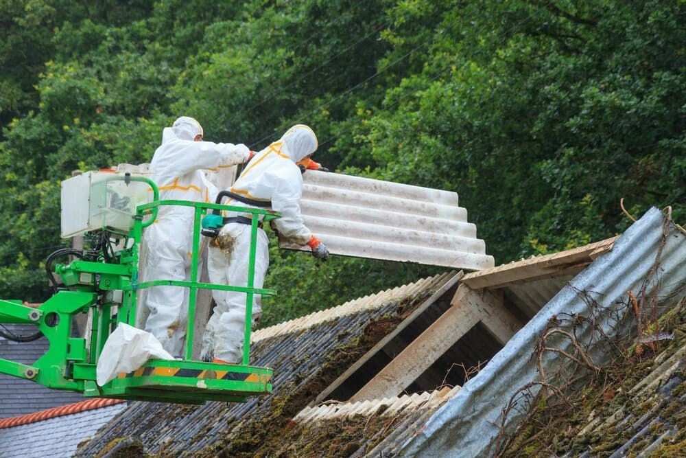 Two Workers in Protective Suits Removing Asbestos Roofing From a Building — Dirt Werx in Ulladulla, NSW