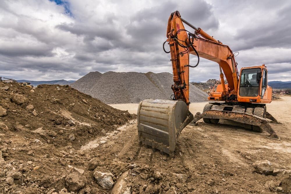 Orange Excavator Digging Into Dirt, Pile of Gravel — Dirt Werx in Nowra, NSW