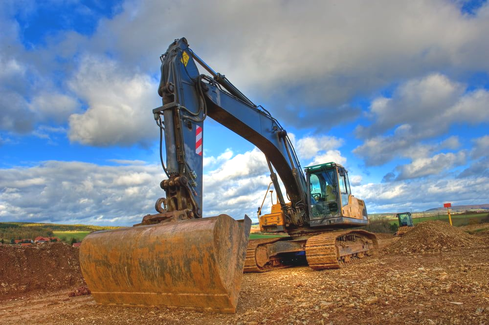 Excavator on a Construction Site, Blue and Gold, Against a Cloudy Sky — Dirt Werx in Kiama, NSW