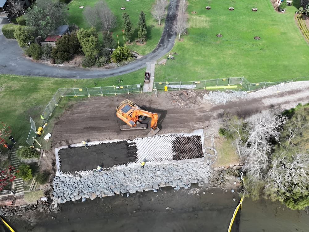 Aerial view of excavator on a construction site next to a body of water and green park — Dirt Werx in Ulladulla, NSW