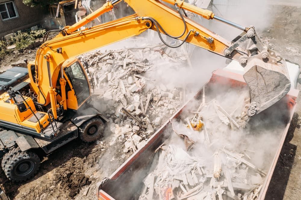 Yellow Excavator Loading Debris Into a Red Dump Truck at a Construction Site — Dirt Werx in Wollongong, NSW
