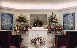 Decorated funeral altar with floral arrangements and casket in a chapel