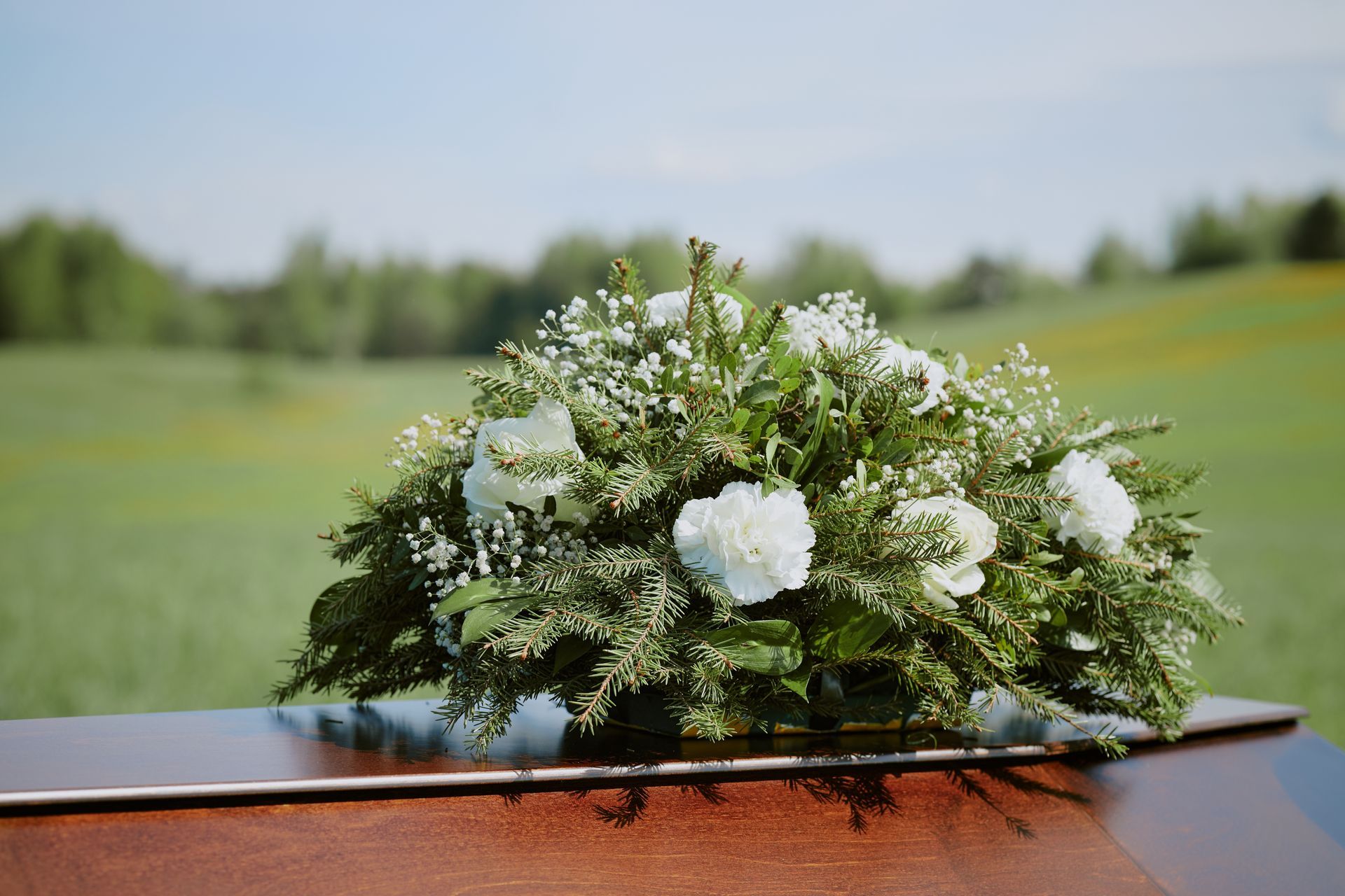 White floral bouquet on a wooden surface with a blurred green outdoor background