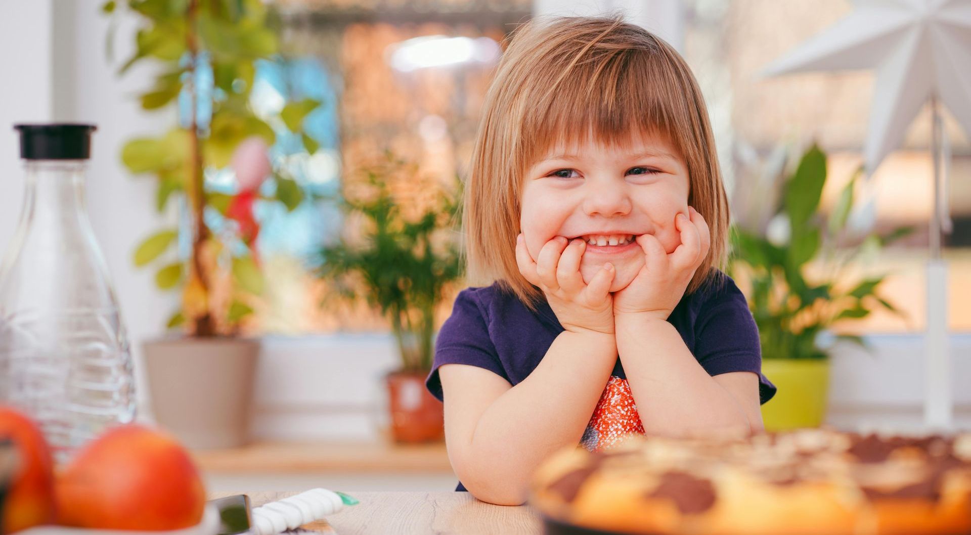 A little girl is sitting at a table with a cake in front of her.