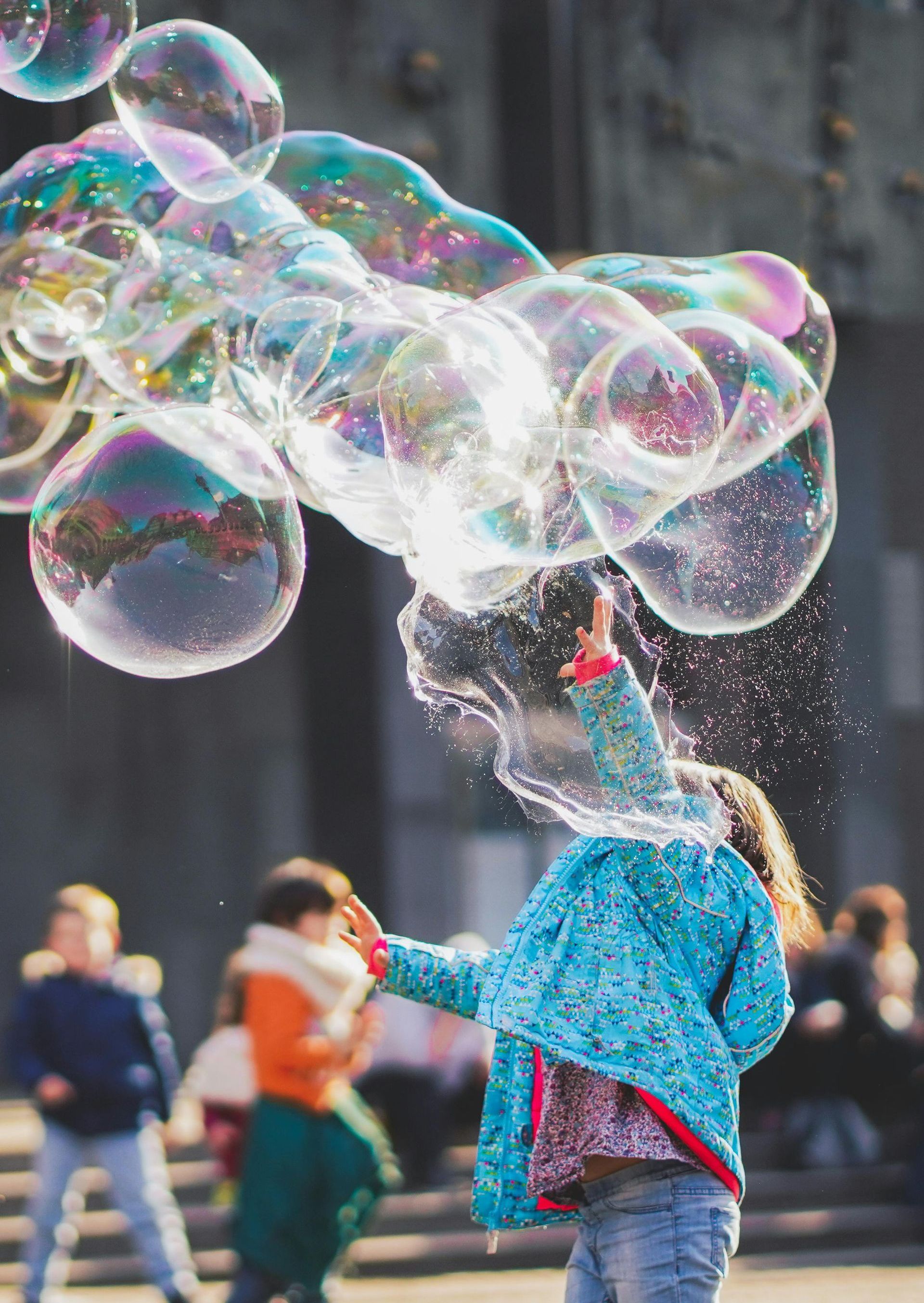 A little girl is blowing soap bubbles in the air.