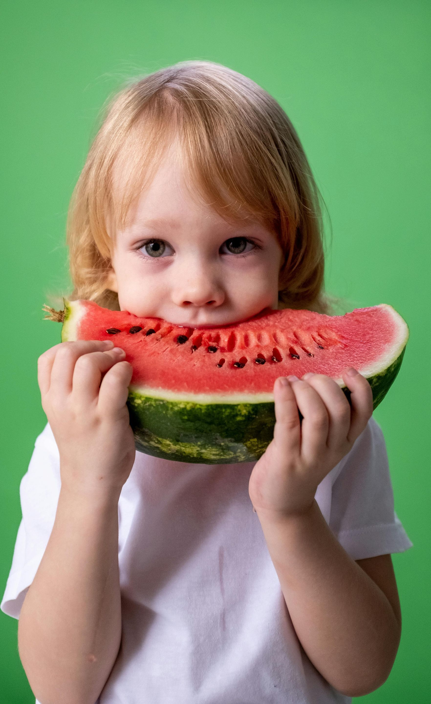 A little girl is eating a slice of watermelon.