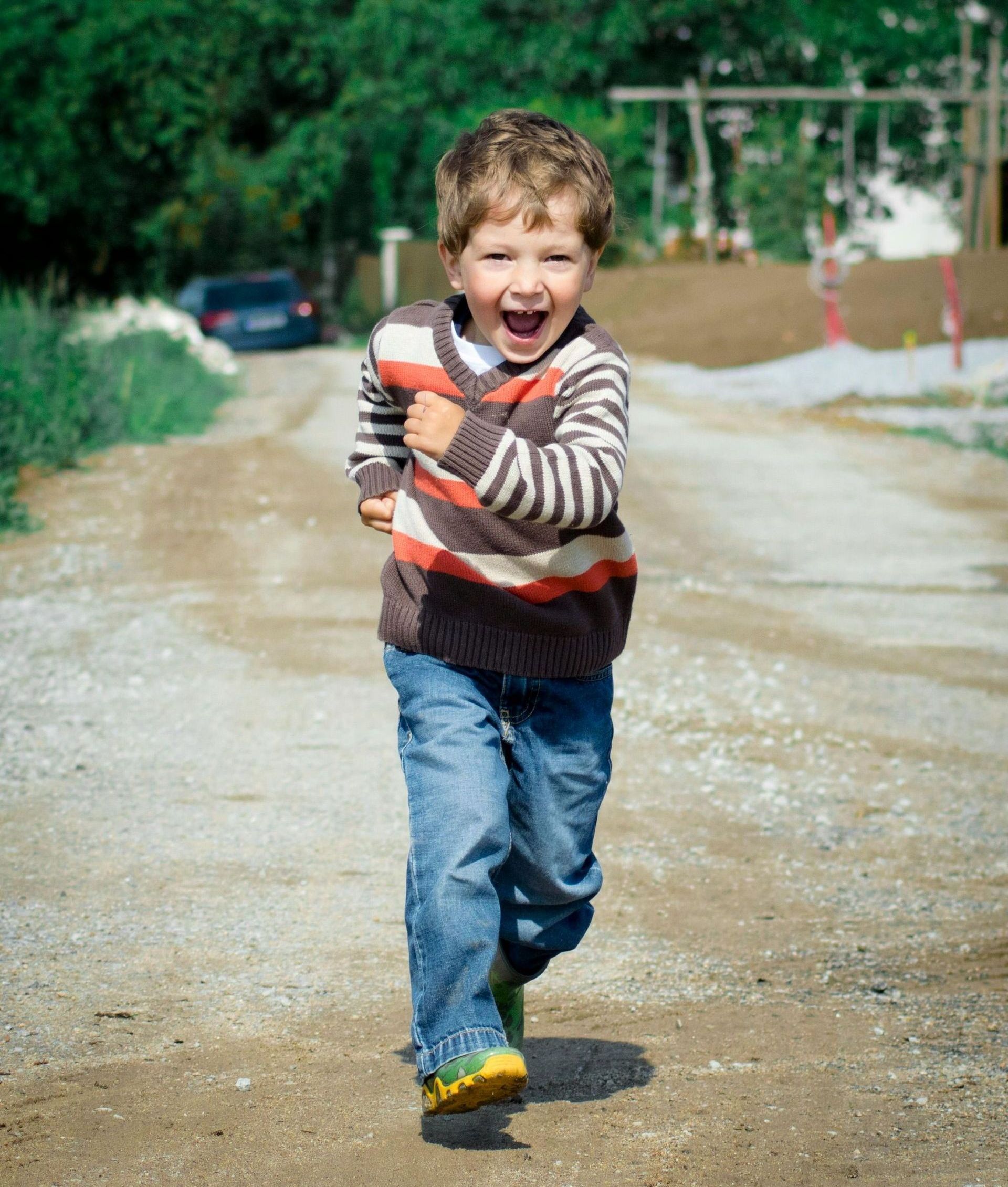 A young boy is running down a dirt road.